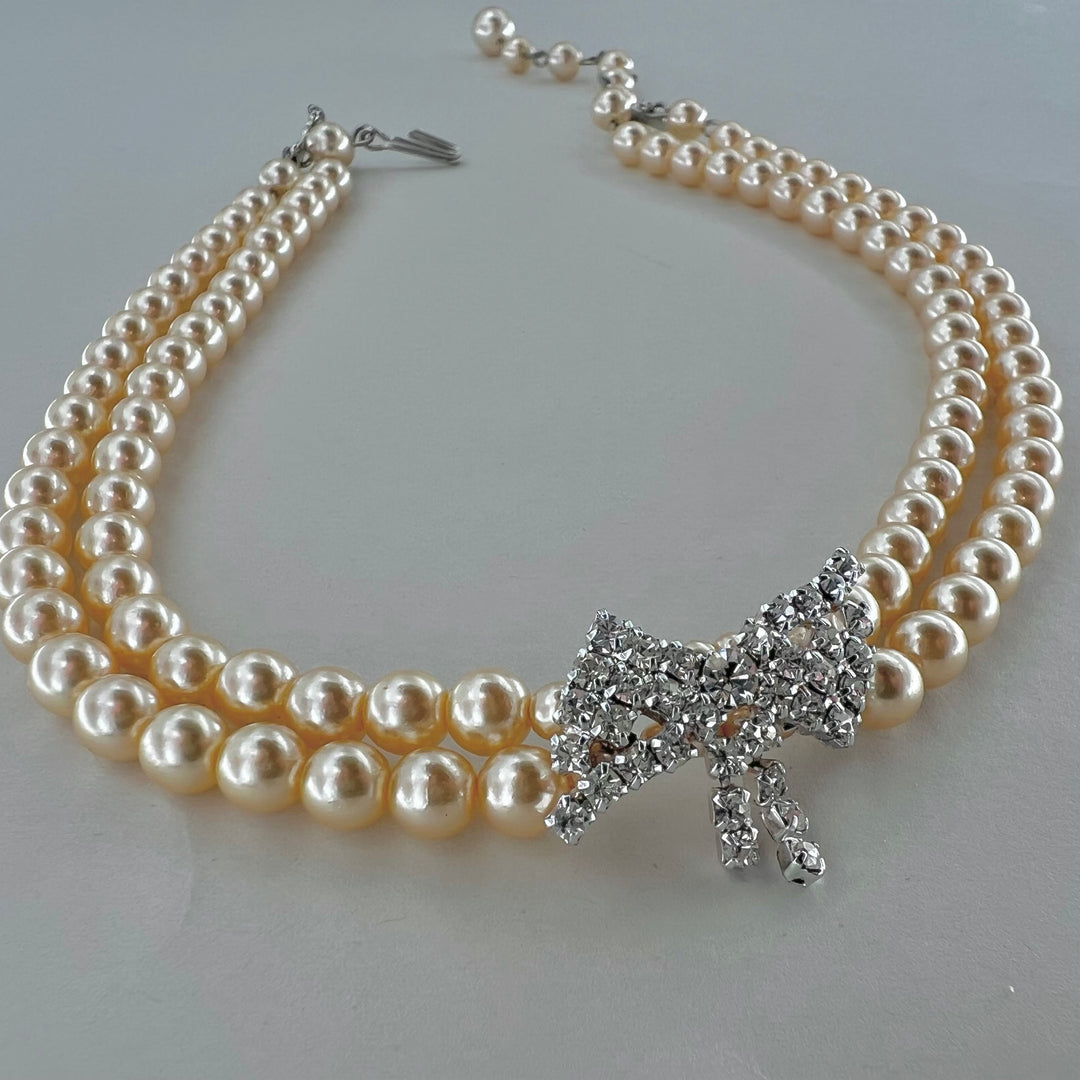 Find Halskæde, choker med beige voksperler og sløjfe vedhæng, forsølvet messing hos Beadhouse of Copenhagen i dag, med en altid hurtig levering!